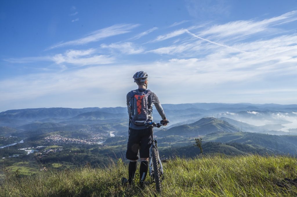 Ciclista numa paisagem natural, com capacete e bicicleta. Para sua rotina de ciclismo, ele pode usar o app Strava