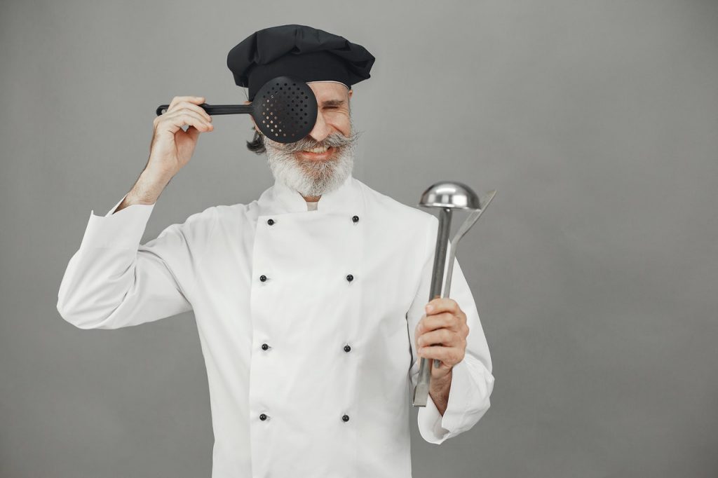 Chef segurando utensílios de cozinha como concha e escumadeira