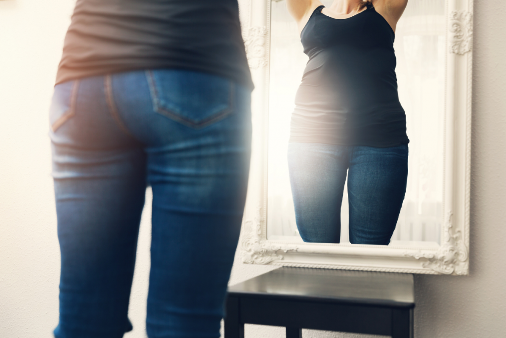Mulher se olhando no espelho se achando acima do peso