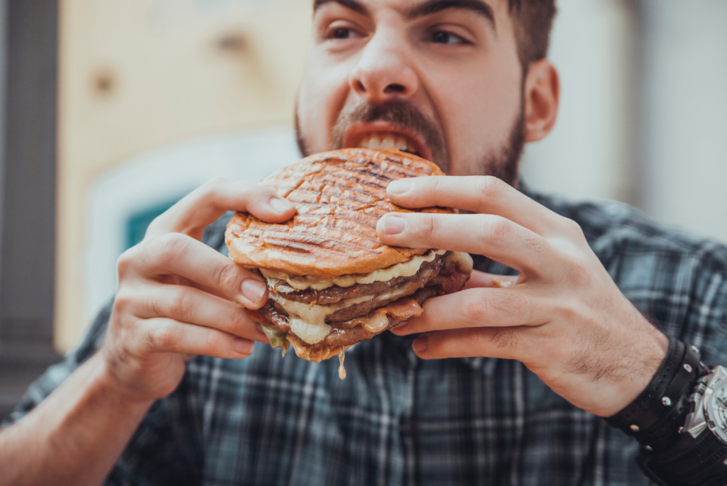 Homem comendo hambúrguer grande