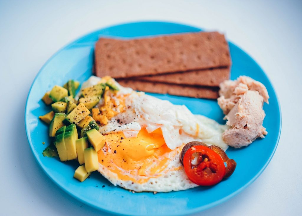 prato azul com ovos, abacate, bolachas e tomate