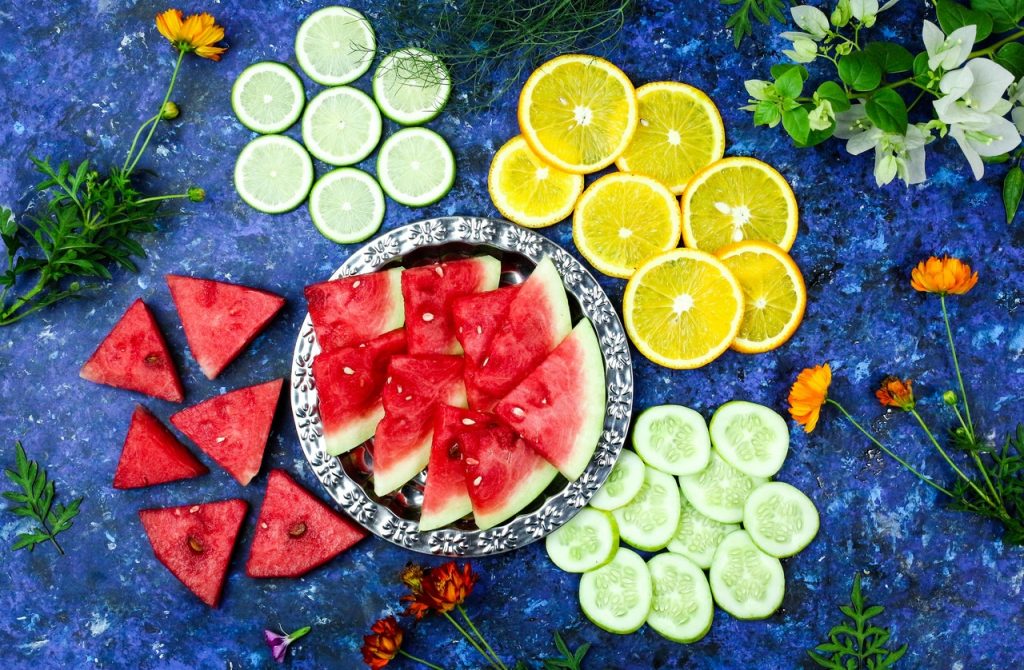 mesa de frutas com fatias de melancia, pepino, limões e laranjas