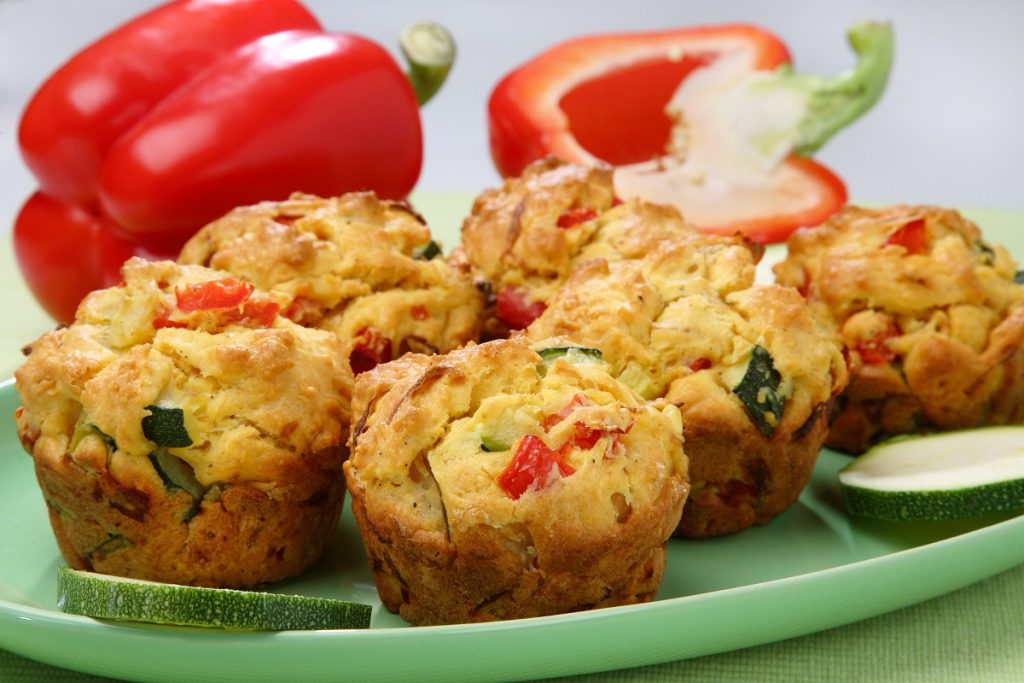 muffin de legumes em prato verde; ao fundo, pimentões vermelhos