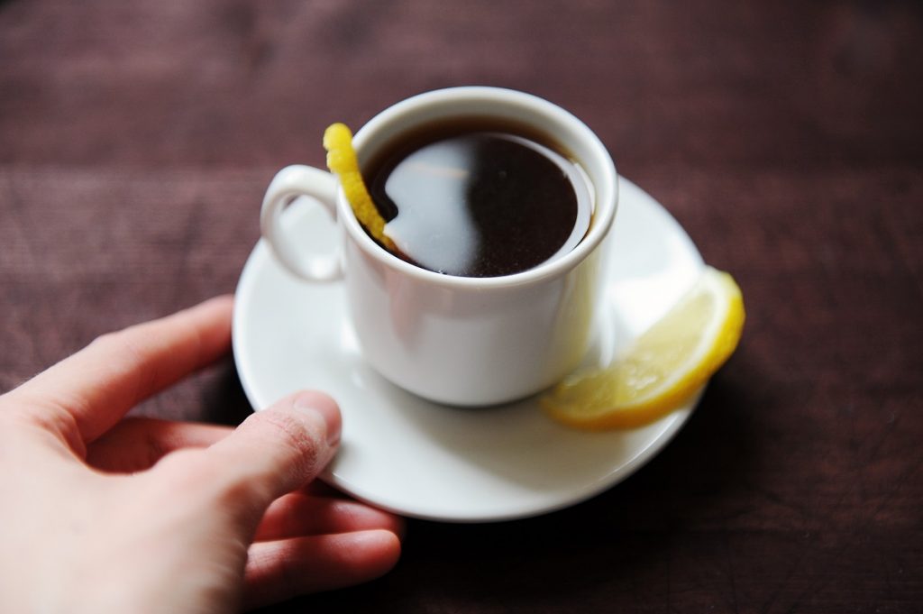 pessoa segurando xícara branca de café com limão