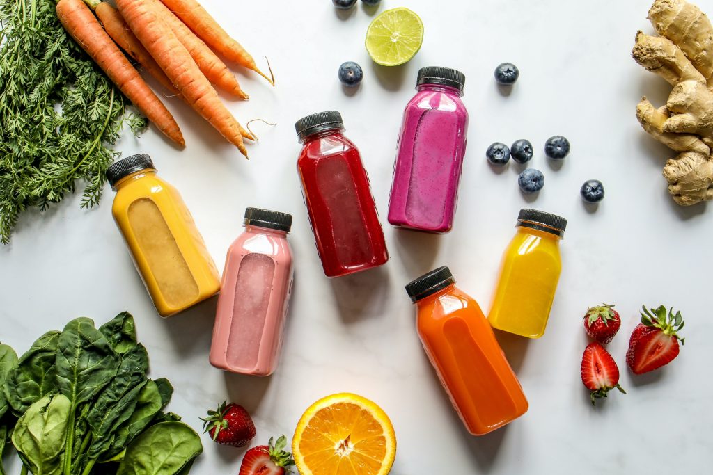 imagem com diversas garrafas de suco detox ao lado de frutas e verduras