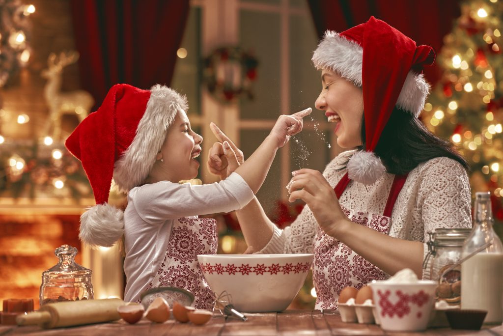 Mãe e filha com chapéu de Papai Noel cozinhando