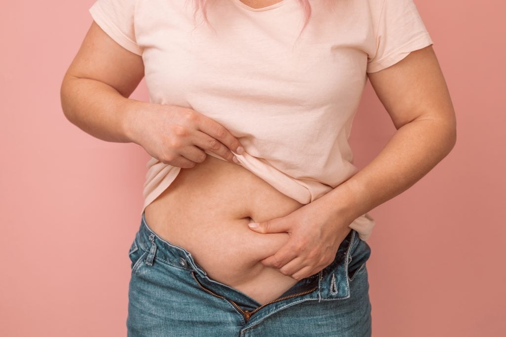 Mulher mostrando barriga com gordura