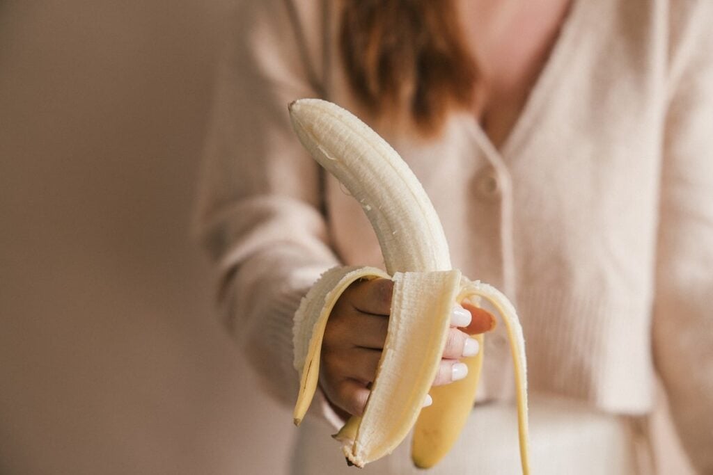 pessoa segurando banana com a casca aberta