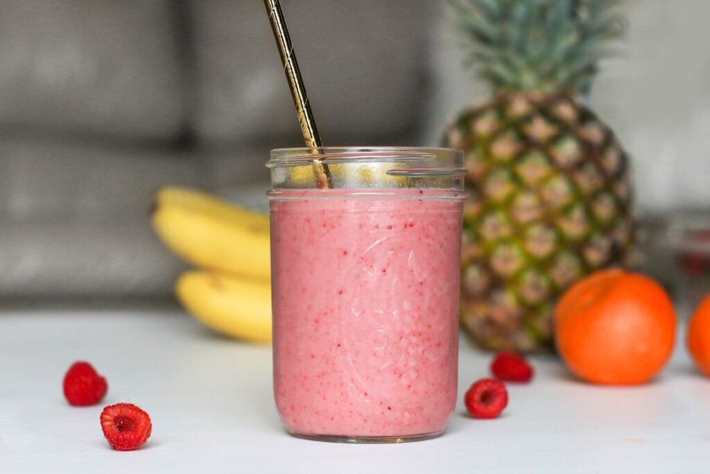 Copo de suco com frutas ao fundo
