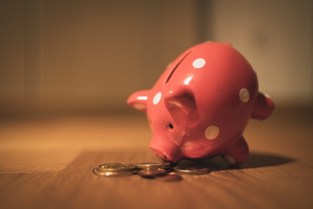 Cofrinho de porquinho cheirando moedas, representando a economia de emagrecer gastando pouco