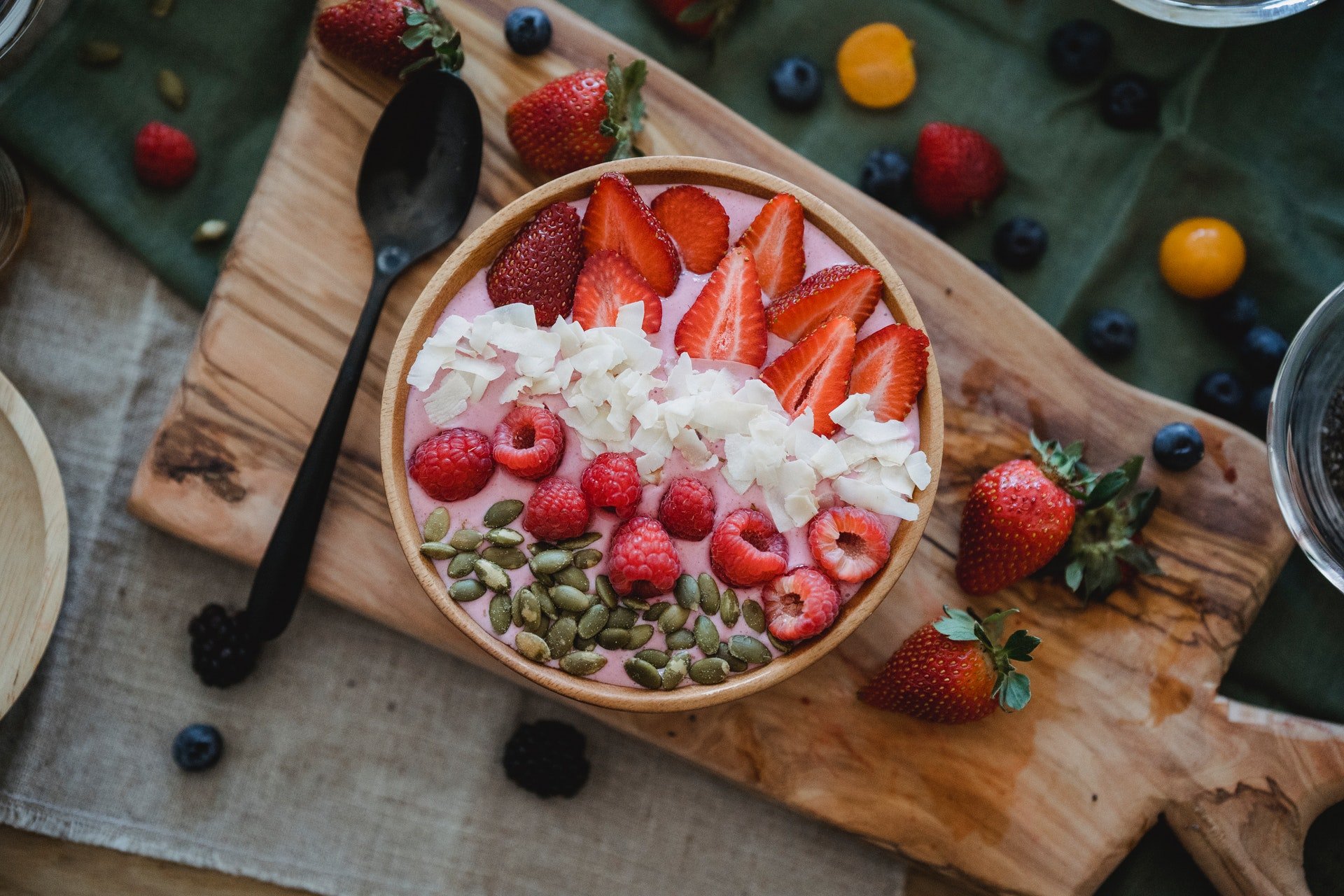 Tigela com creme e frutas vermelhas em cima de tábua