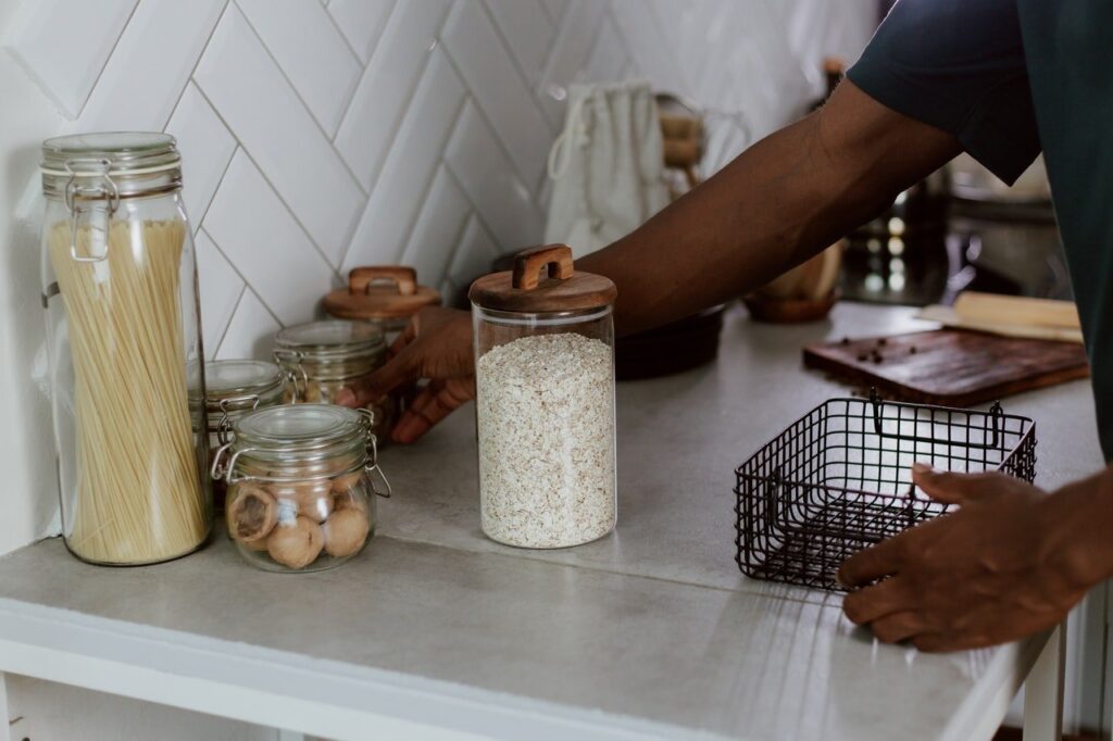 Pessoa arrumando bancada da cozinha com potes de alimentos