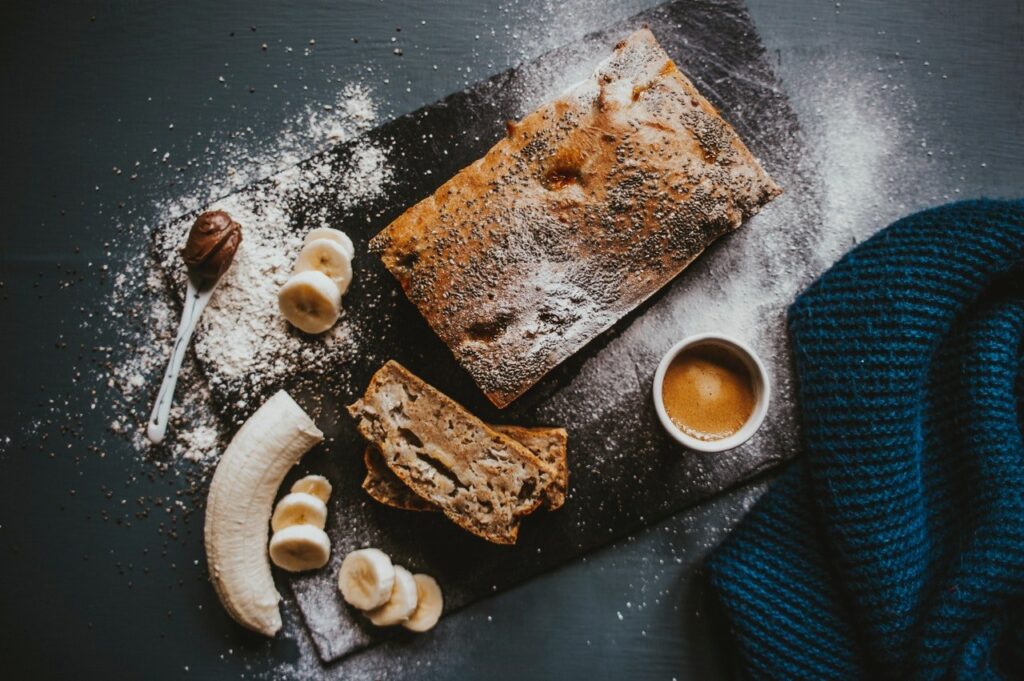 Bolo de banana sobre a mesa com bananas, farinha e possivelmente canela.