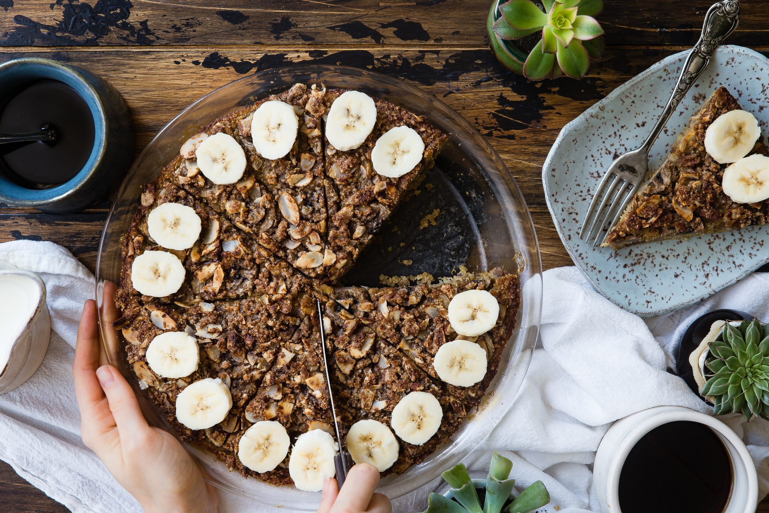 Bolo de banana sendo fatiado e servido, com rodelas de banana na parte superior