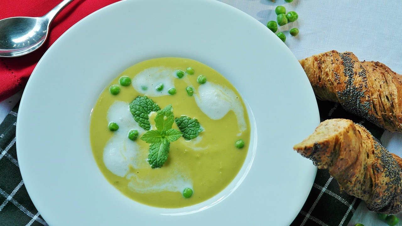 Prato branco com caldo verde, creme, ervilhas e hortelã