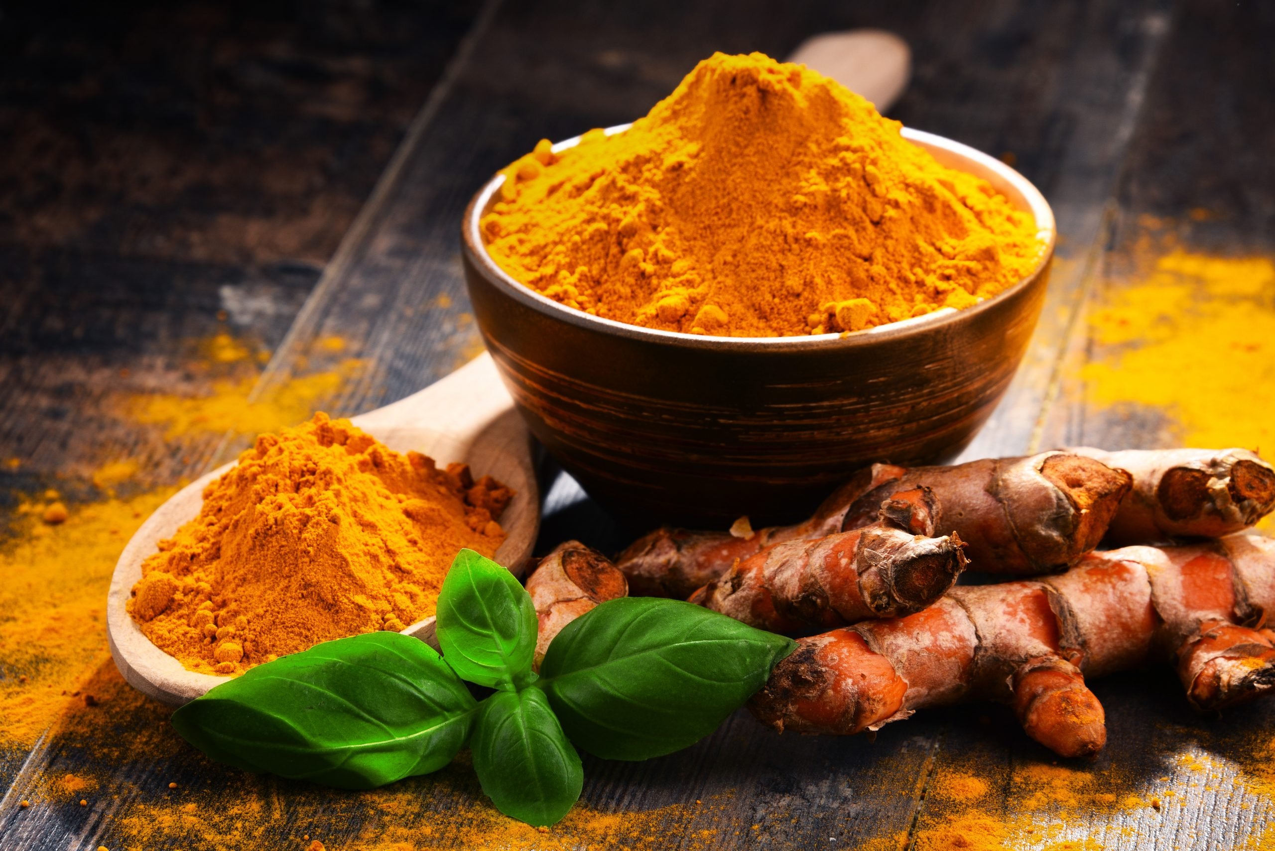 Tigelas com cúrcuma em pó e raiz de cúrcuma