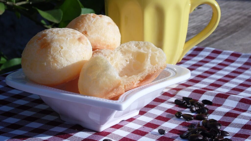 pão de queijo mordido, sem estar cru por dentro, caneca amarela ao fundo