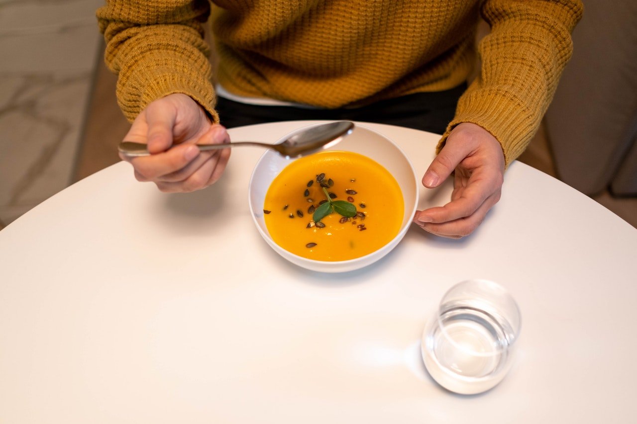 Pessoa tomando sopa, copo de água