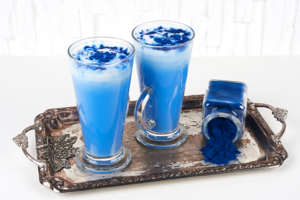 Copos e pó de spirulina azul na bandeja de prata