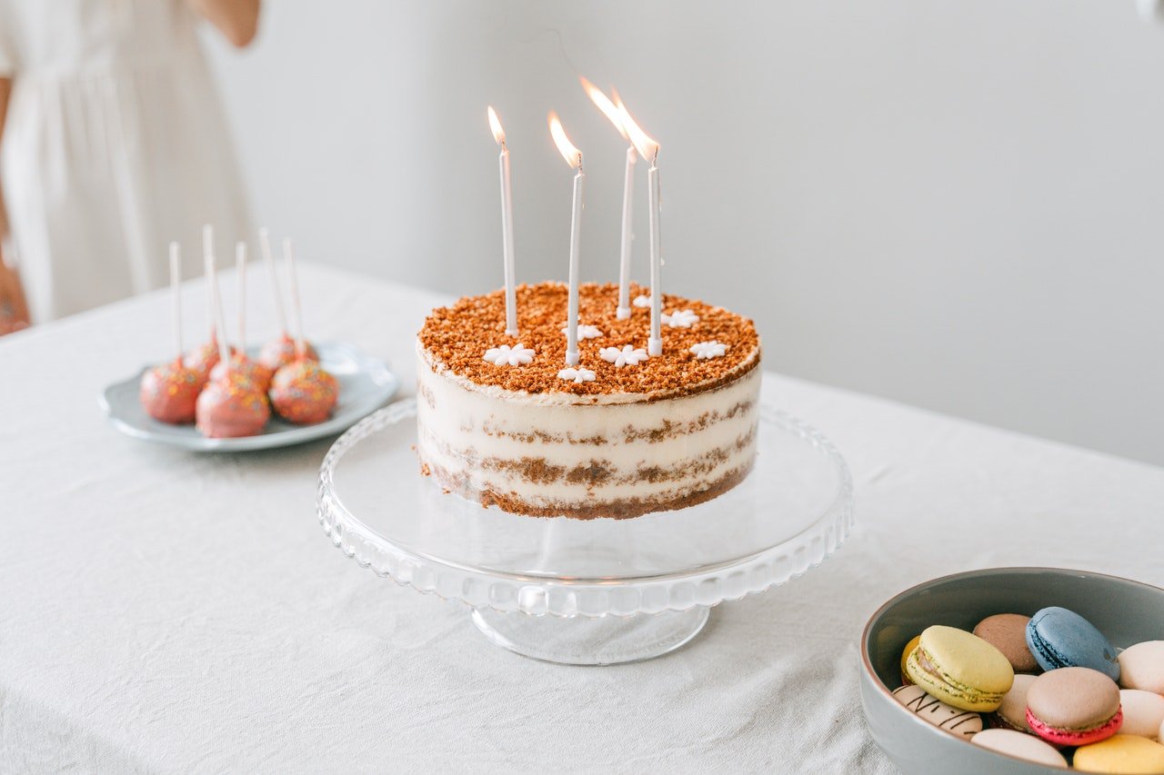 Bolo de aniversário branco com velas e enfeites na mesa