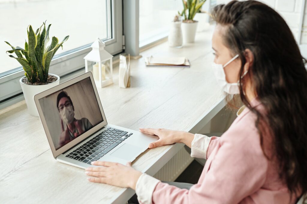 Mulher fazendo consulta online com médico, ambos de máscara
