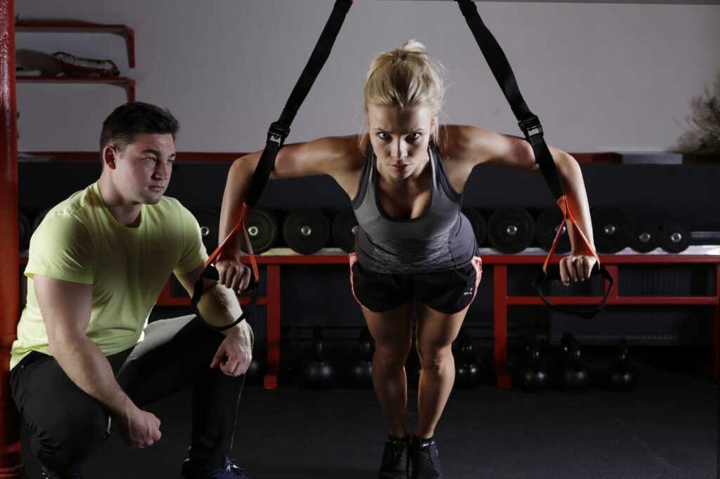 Mulher fazendo musculação com treinador