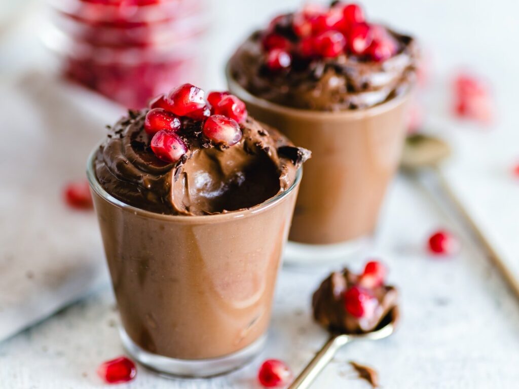 Dois copos de vidro com mousse de leite ninho com chocolate e frutas vermelhas para decorar