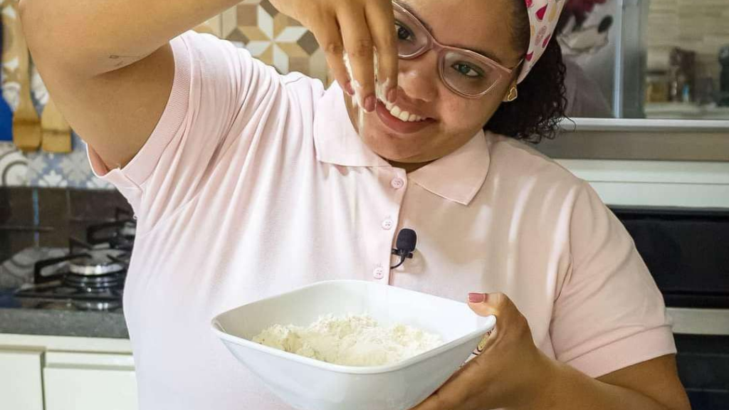 Mari colocando açucar de confeiteiro num pote branco, foto de divulgação do Curso de confeitaria Mundo Doce da Mari