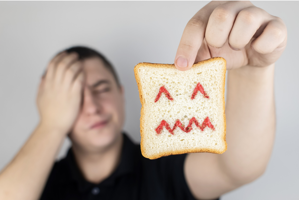 Homem segurando pão com cara de dor