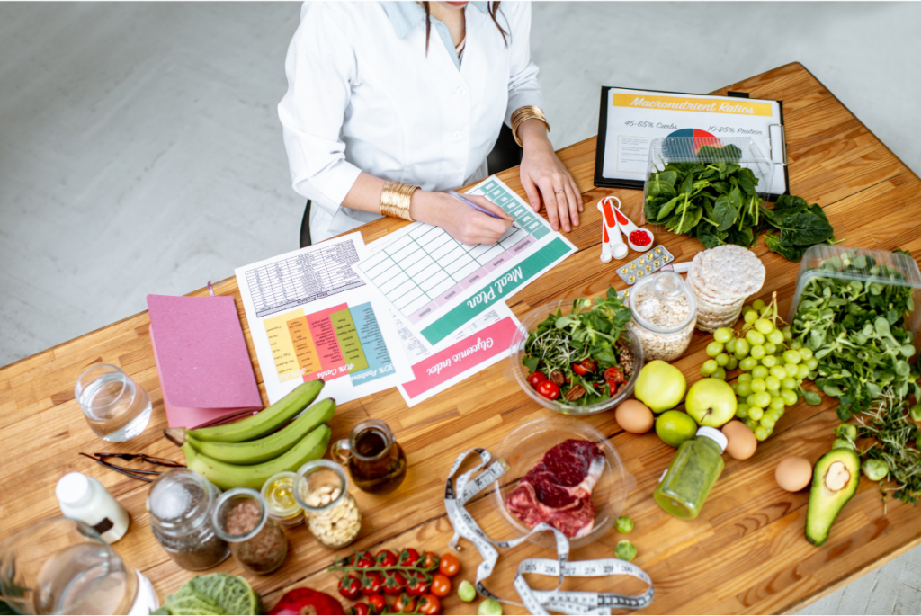 Nutricionista com livros e alimentos na mesa