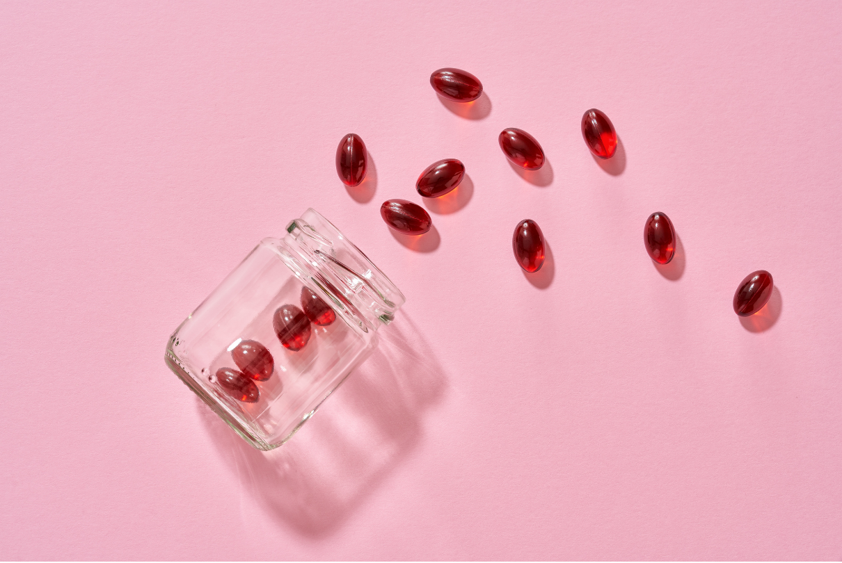 Pote transparente com cápsulas vermelhas em fundo rosa