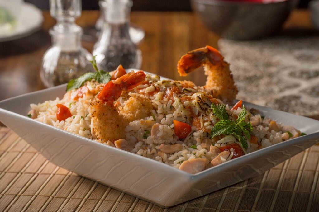 Camarão empanado sobre prato de arroz.