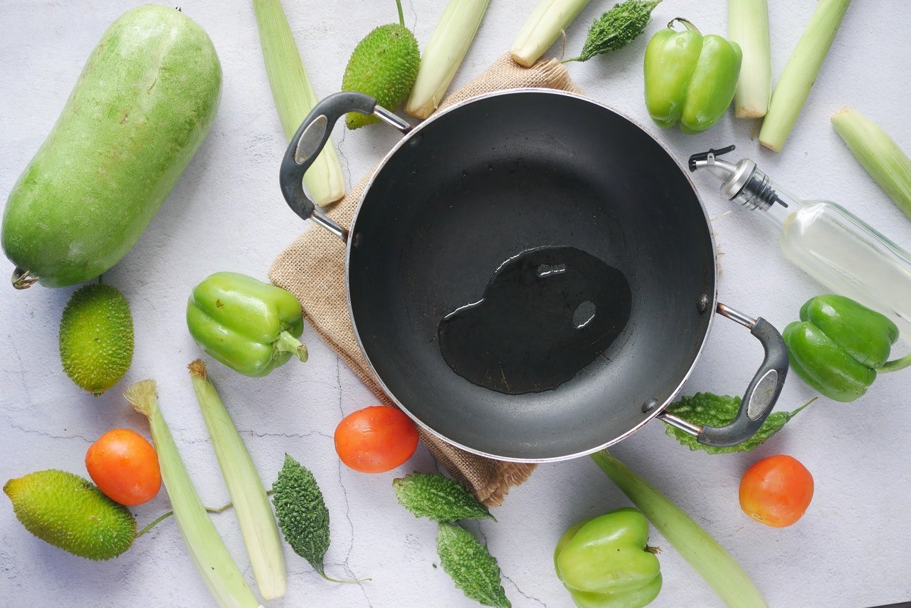 verduras e legumes frescos ao lado de uma panela com azeite
