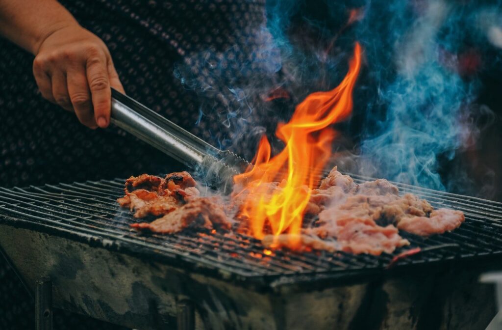 pessoa cozinhando carne na grelha
