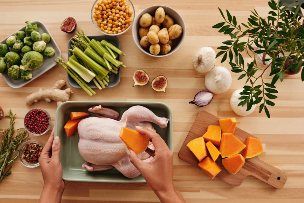 imagem com frango inteiro, legumes e temperos
