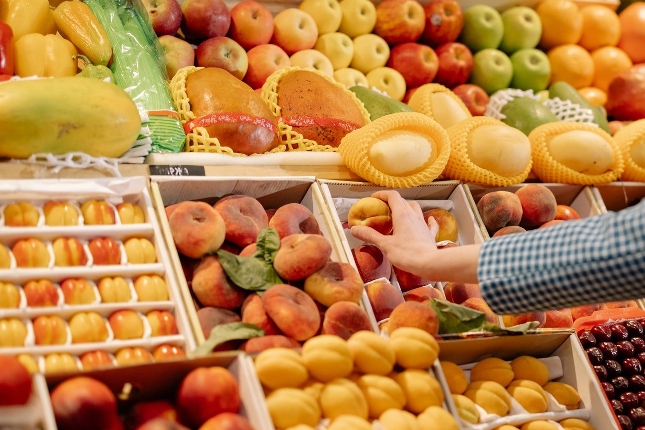 pessoa pegando fruta que emagrece na banca de frutas