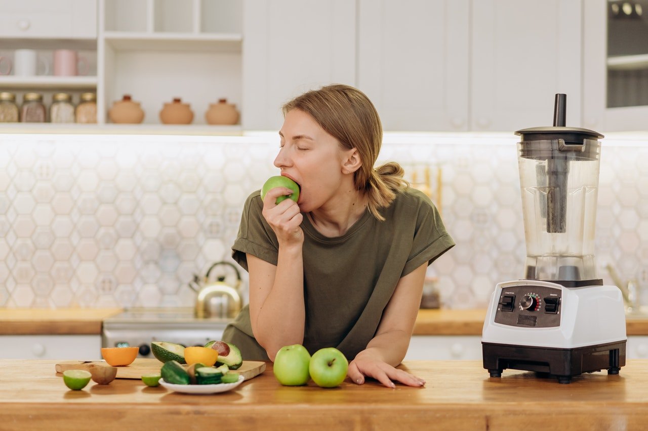 pessoa comendo fruta na cozinha