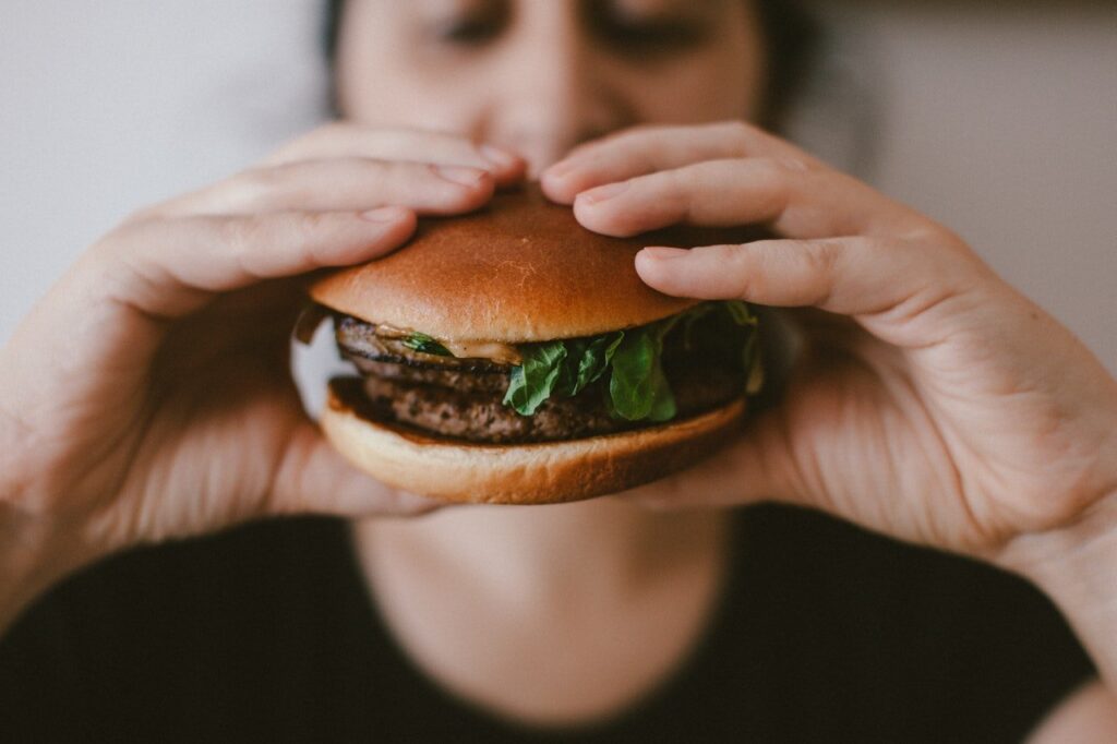pessoa comendo lanche com hambúrguer vegano