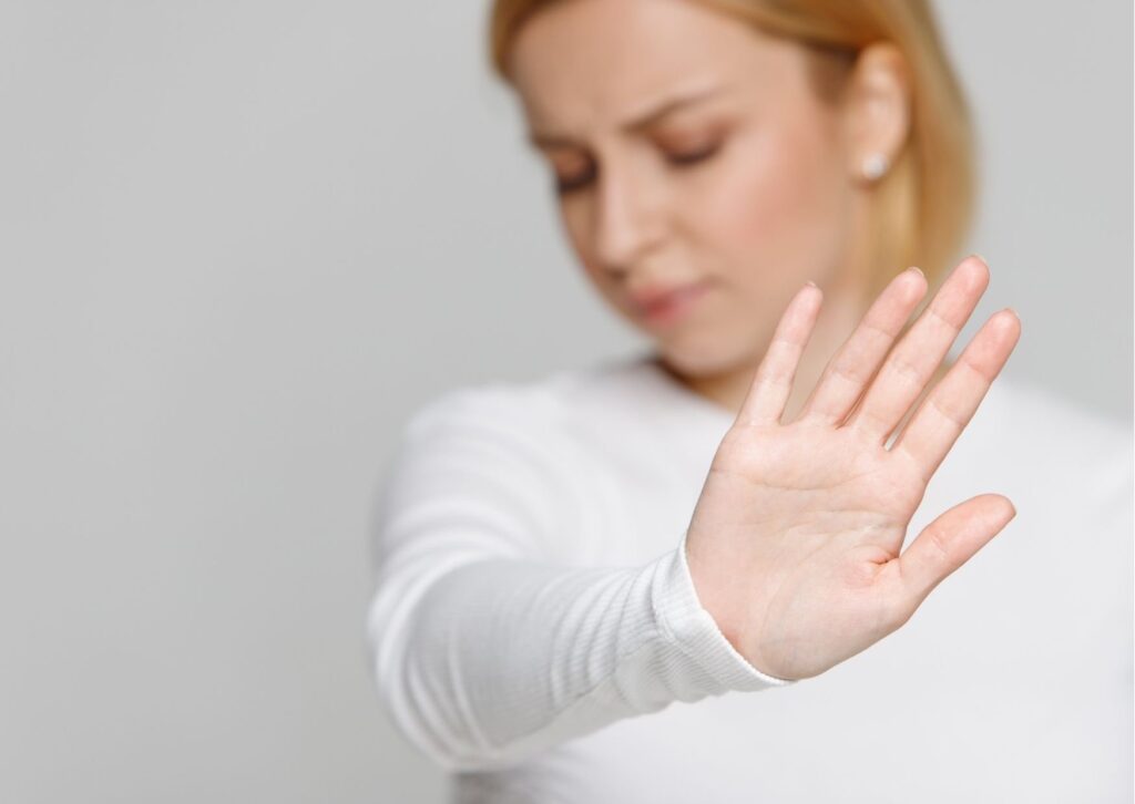 mulher de blusa branca fazendo sinal de pare com a mão