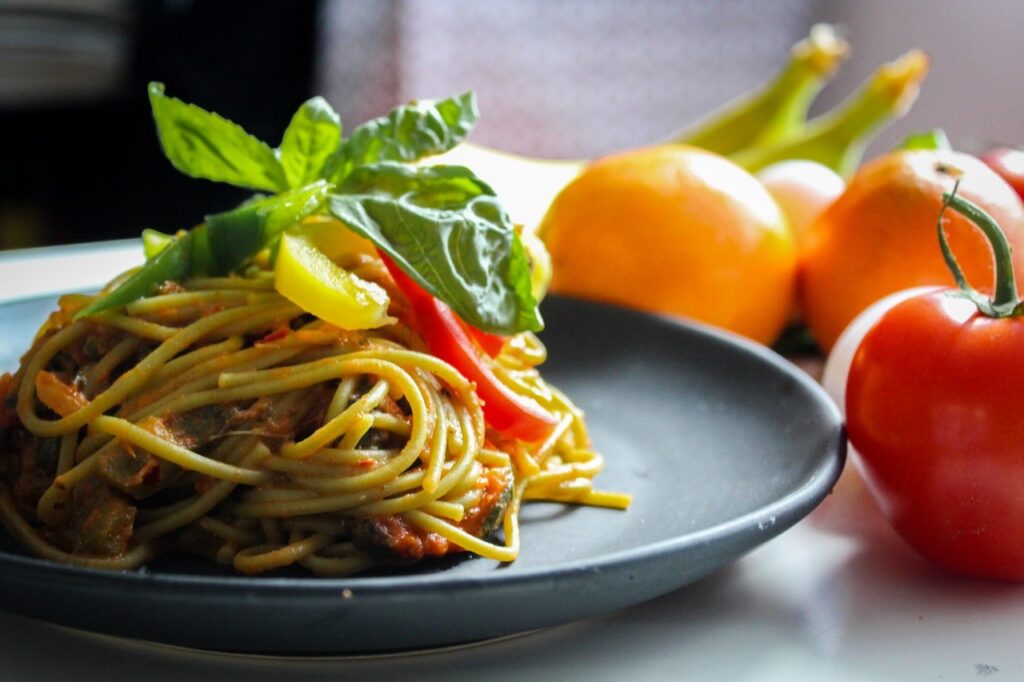 prato cinza de macarronada com tomates ao lado