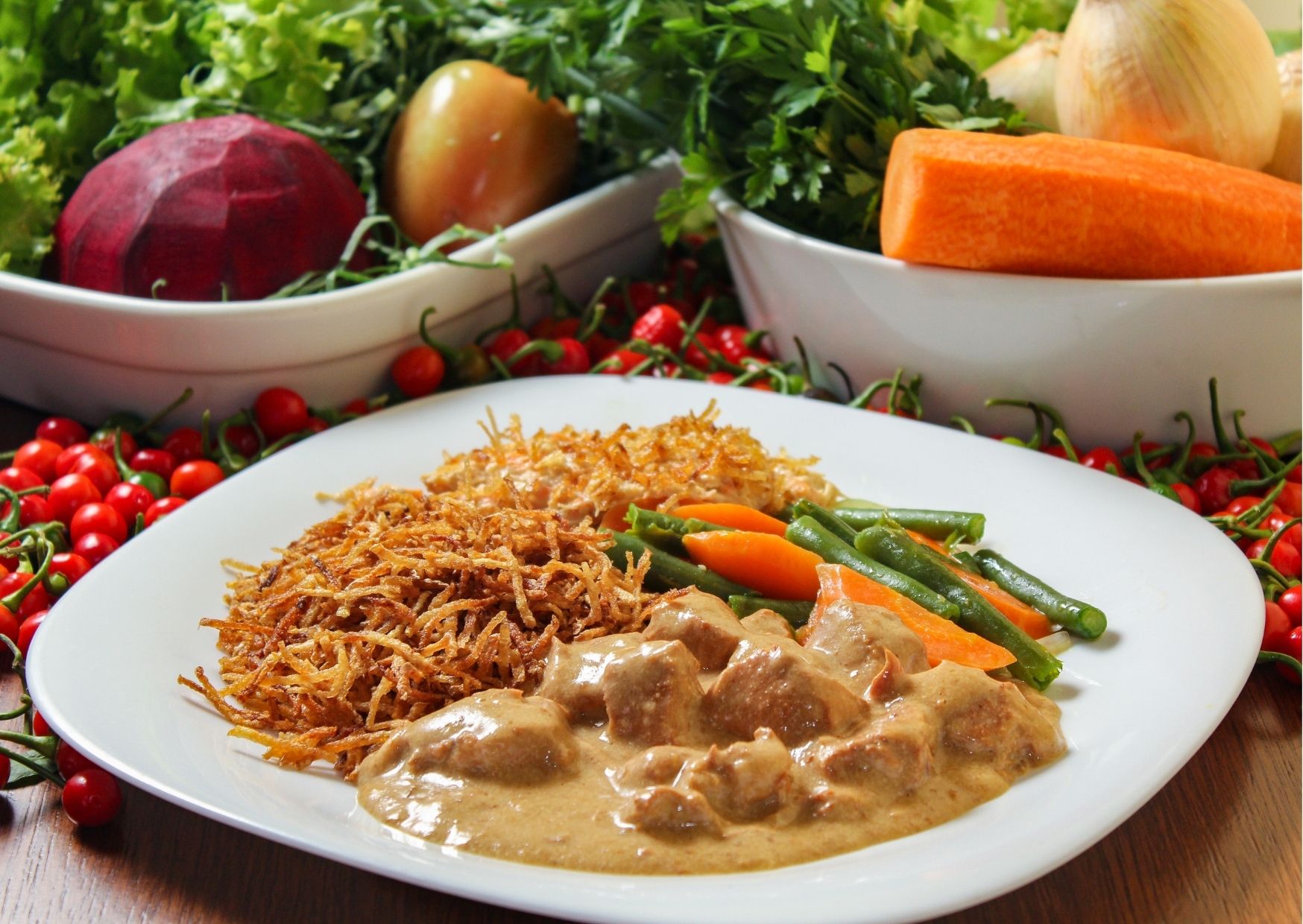 prato branco com estrogonofe de frango e batata palha; ao lado frutas e verduras