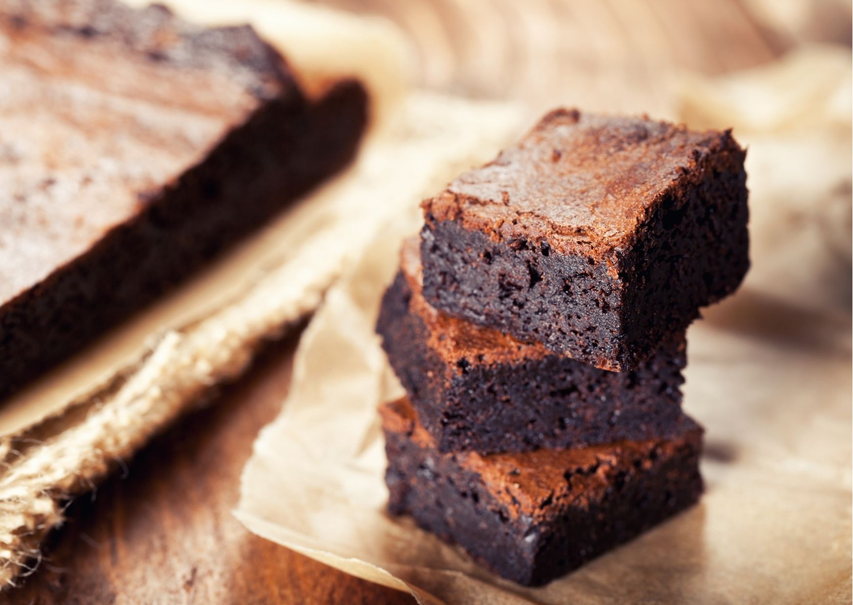 imagem com vários brownies na frente e um tabuleiro de brownie