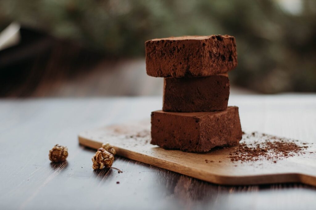 três pedaços cortados de brownie de nescau em cima de tábua de madeira