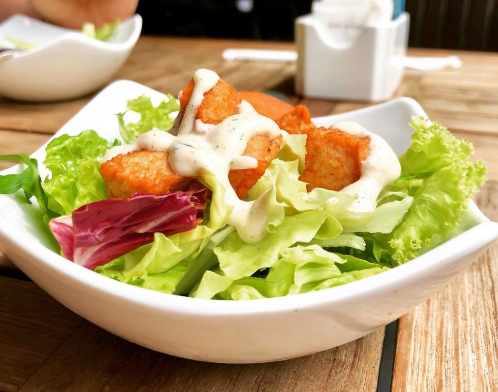 pote branco de salada com frango e molho