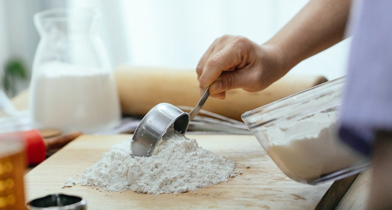 pessoa espalhando farinha para fazer uma massa de bolo de aniversário