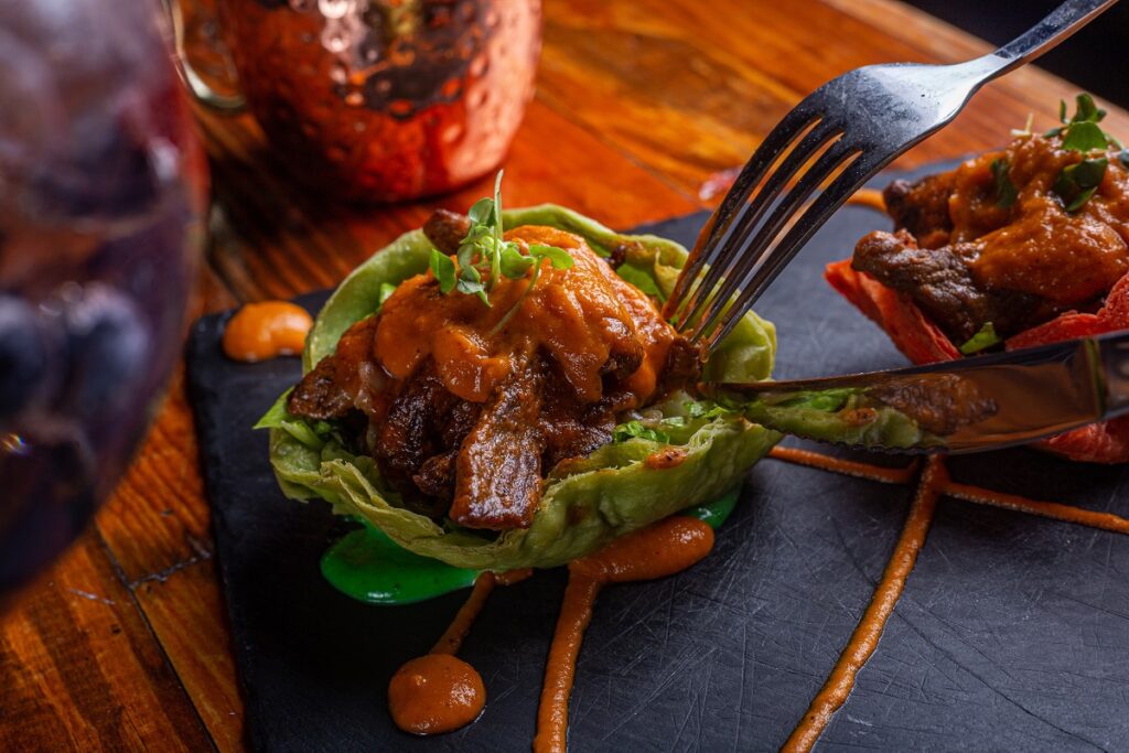 pessoa cortando pedaço de carne suína coberta com molho