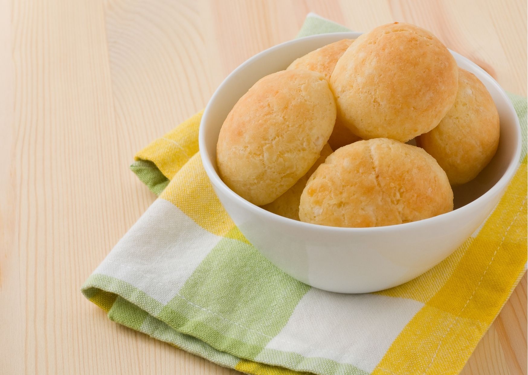 pão de queijo fitness em tigela branca; embaixo da tigela há uma toalha xadrez