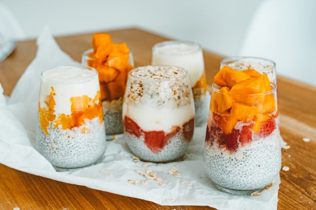 diversos potes de vidro transparentes com iogurte, frutas e aveia