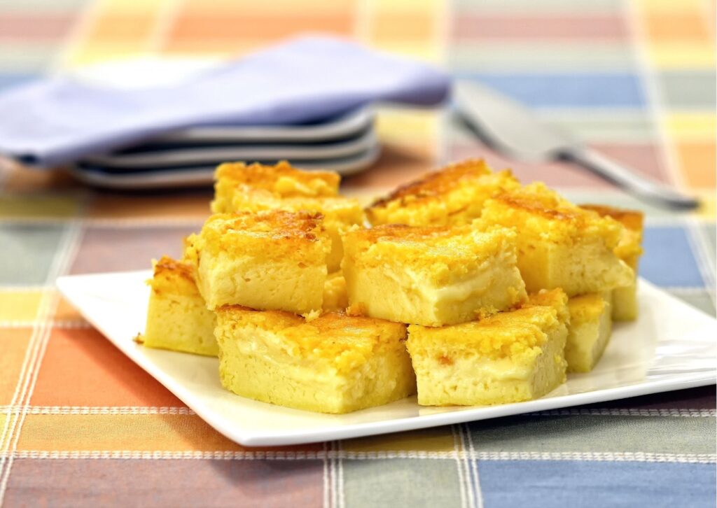 bolo de milho cortado em prato branco, que está em cima de uma toalha xadrez