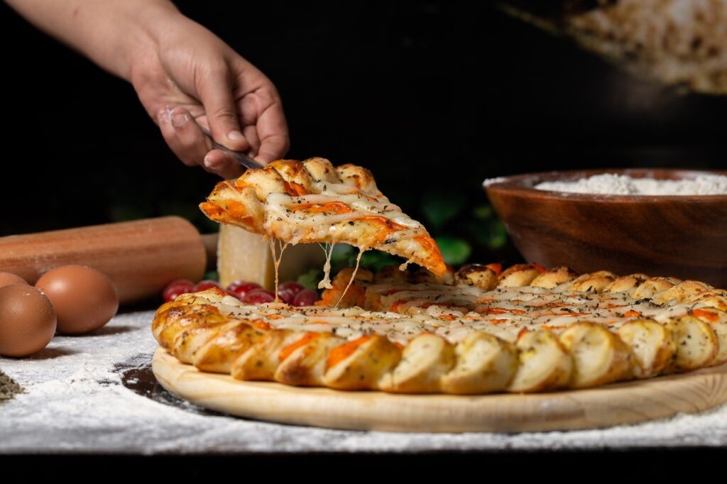 pessoa pegando pedaço de pizza para comer